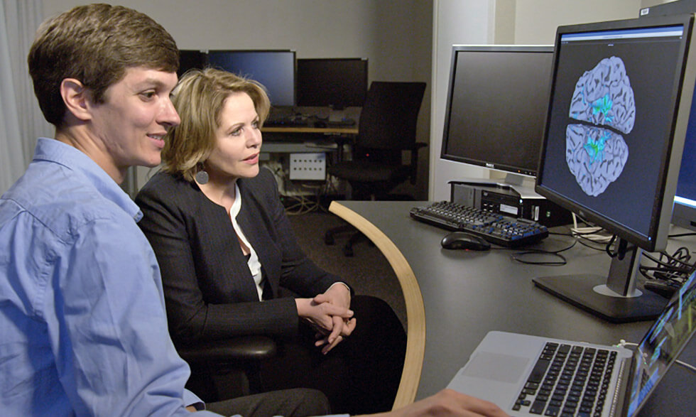 National Institute of Mental Health researcher David Jangraw, Ph.D. (left), reviews brain scans with Renée Fleming at NIH. 