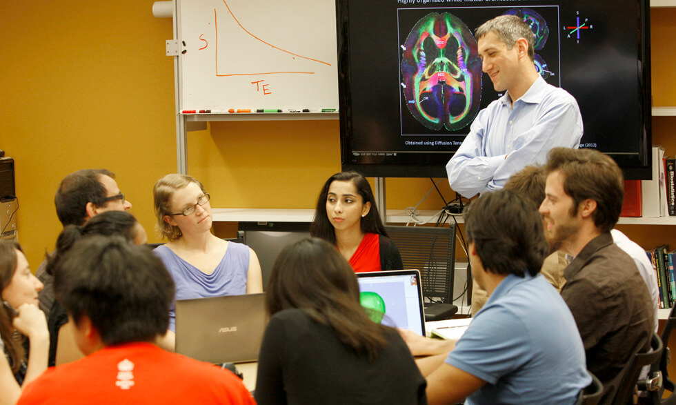 Daniel Reich, M.D., Ph.D. (standing) listens to team members at NIH. 
