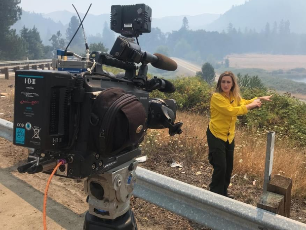 Kelsey Christensen reporting with a camera on the side of the road in Oregon.