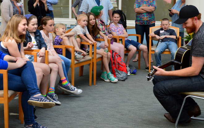 Eric Paslay playing guitar to a group of children.